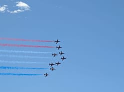 Záběr na devítičlennou formaci Red Arrows zanechávající za sebou typickou červeno-bílo-modrou kouřovou stopu.