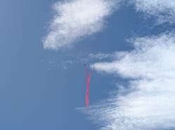 Dynamický záběr na dva letouny Red Arrows (tzv. Synchro Pair) při manévru, kdy se proti sobě řítí a zanechávají kouřovou stopu.