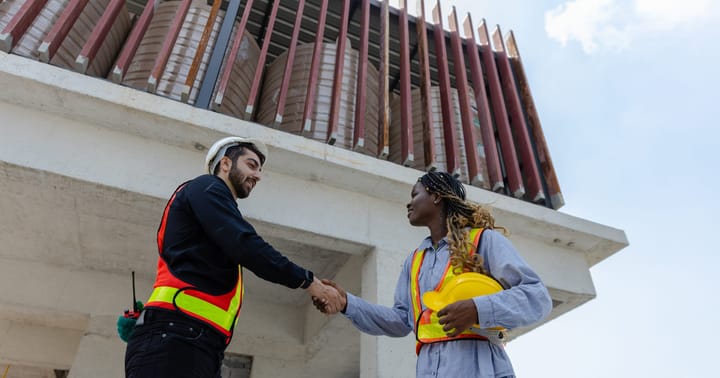 dva lidé u stavby si podávají ruku
