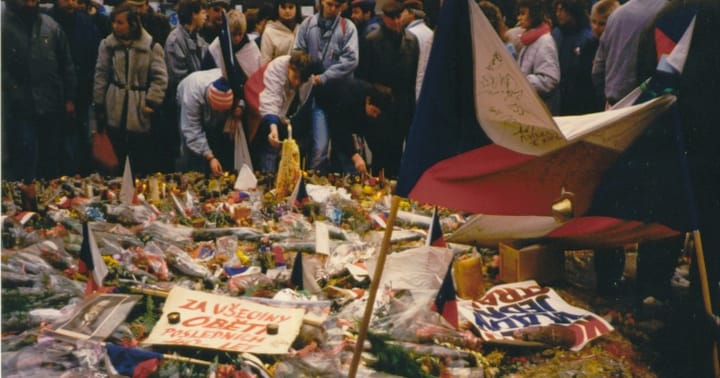 Květiny, vlajky a masy lidí na Václavském náměstí